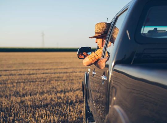 man leaning out of pick up truck at sunset
